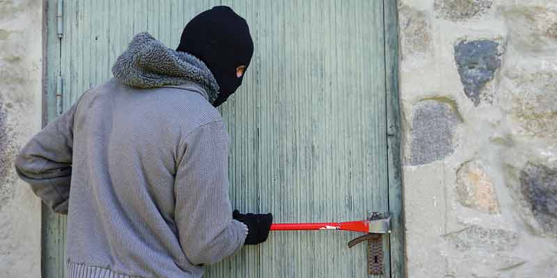 Ein Einbrecher versucht eine Tür aufzuhebeln