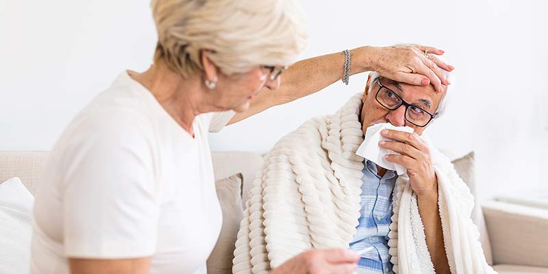 Ältere Frau kümmert sich um kranken älteren Mann