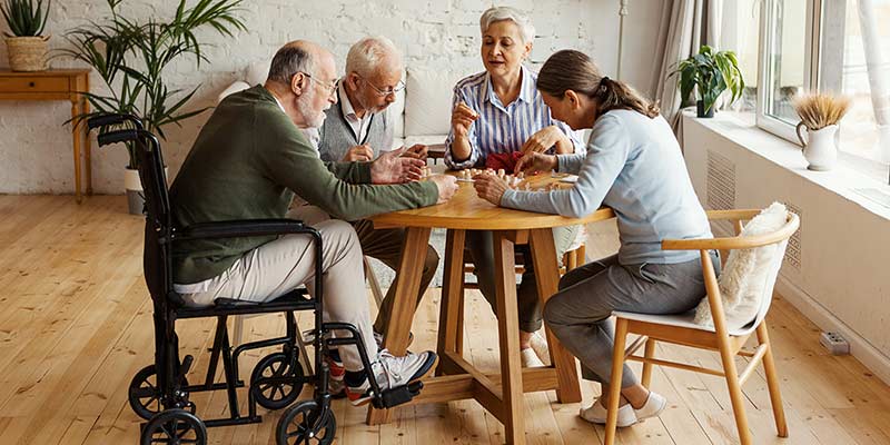 Senioren sitzen gemeinsam an einem Tisch und spielen ein Spiel
