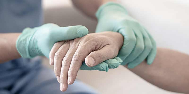 Pflegekraft hält die Hand einer Person; Sterbehilfe bei einem Patienten