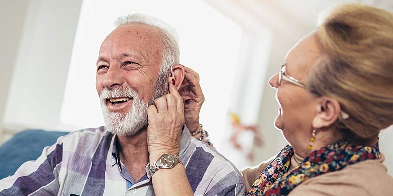 Glücklicher Senior mit Hörgerät im Ohr