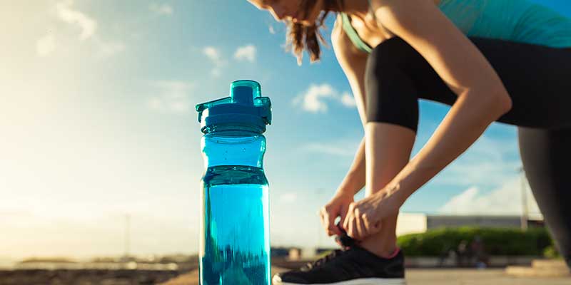 Junge Frau macht Sport im Freien und hat eine Wasserflasche dabei