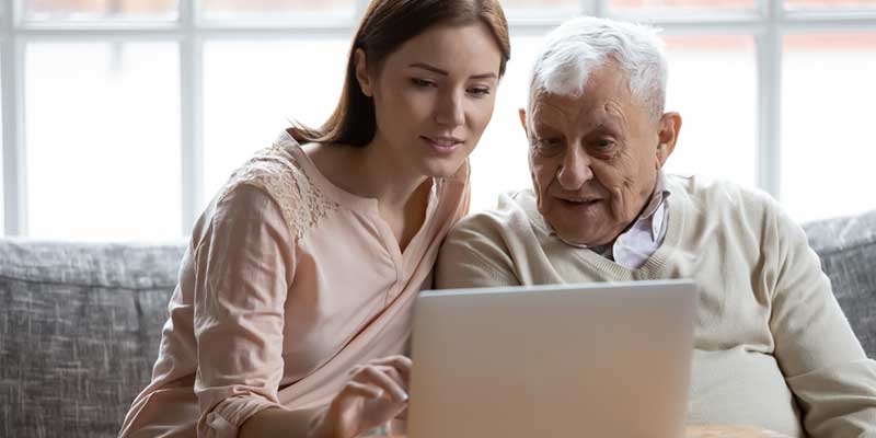 Enkelin und älterer Mann gemeinsam am Laptop.