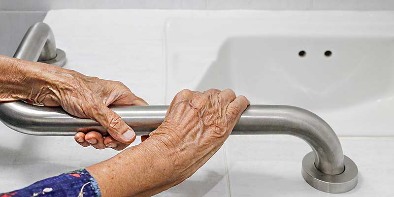 Ältere Frau, die sich im Badezimmer am Handlauf der Badewanne festhält