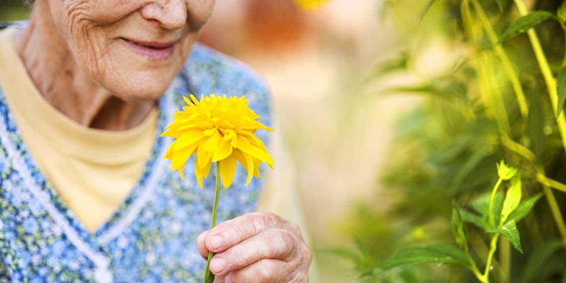 Seniorin hält eine Blume in der Hand