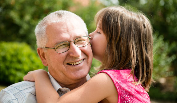 Großvater hält eine lächelnde Enkelin auf dem Arm