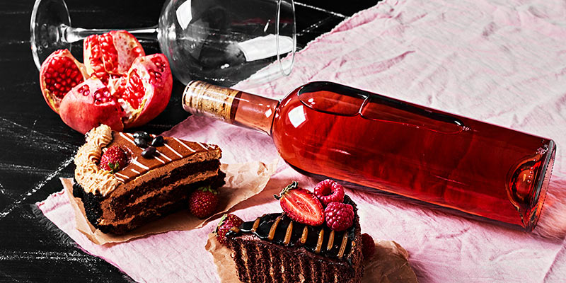 Eine Flasche Wein liegt zusammen mit zwei Stück Schokoladenkuchen
