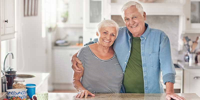 Glückliches älteres Paar steht Arm in Arm in der Küche.