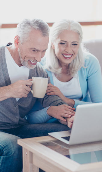 Älteres Paar liest begeistert gemeinsam einen Onlinebeitrag.