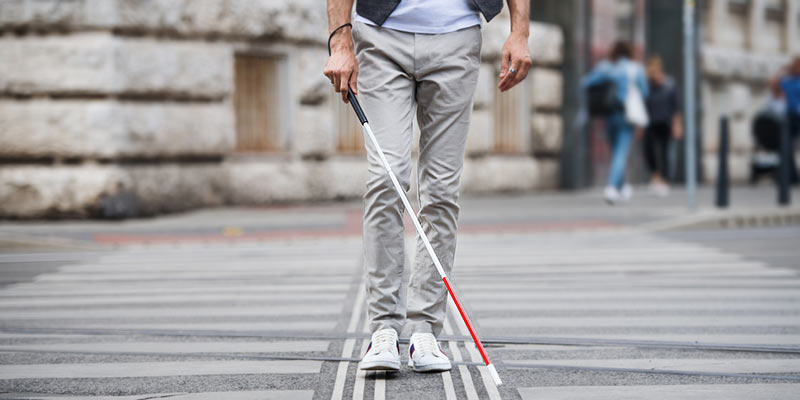 Mann mit Blindenstock auf Straße