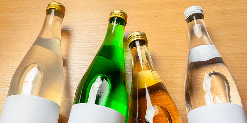 Weinflaschen in verschiedenen Farben liegen auf einem Holztisch