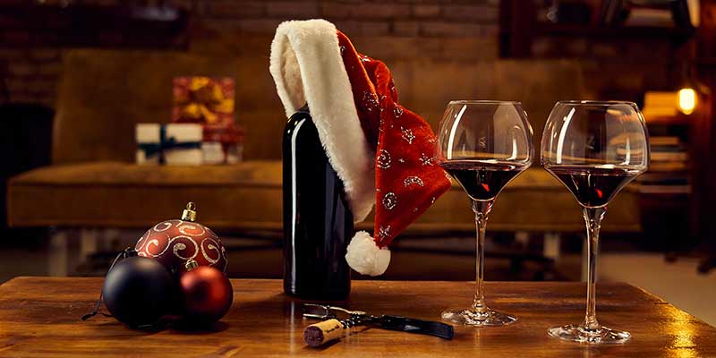 Rotweingläser und Weinflasche auf einem weihnachtlich dekorierten Tisch