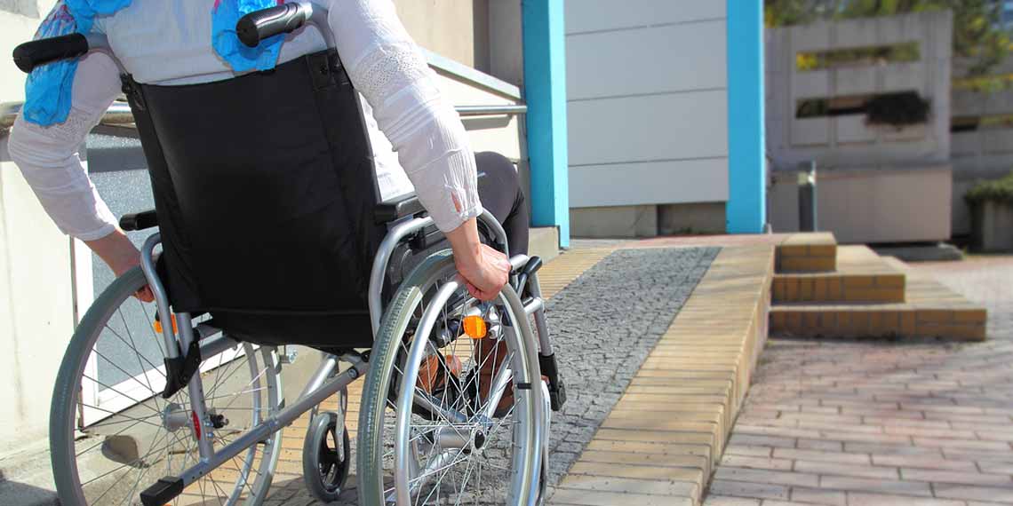 Rollstuhlfahrer auf einer Rampe Richtung Gebäude