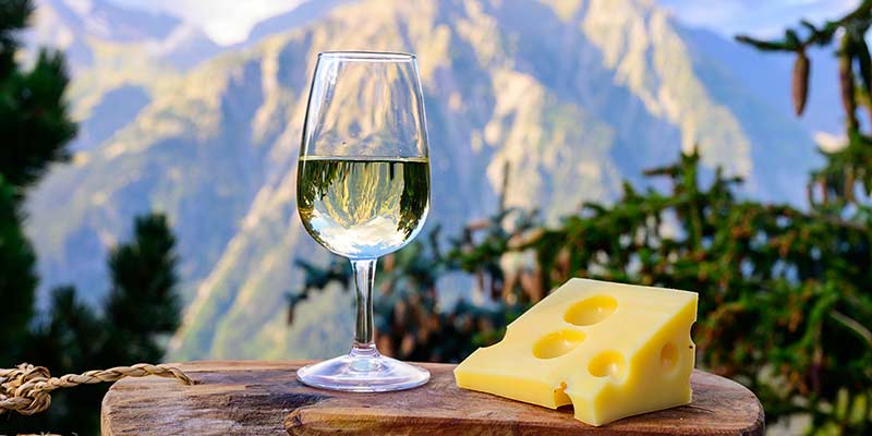 Genussvoller Weißwein und Käse vor einem Bergpanorama