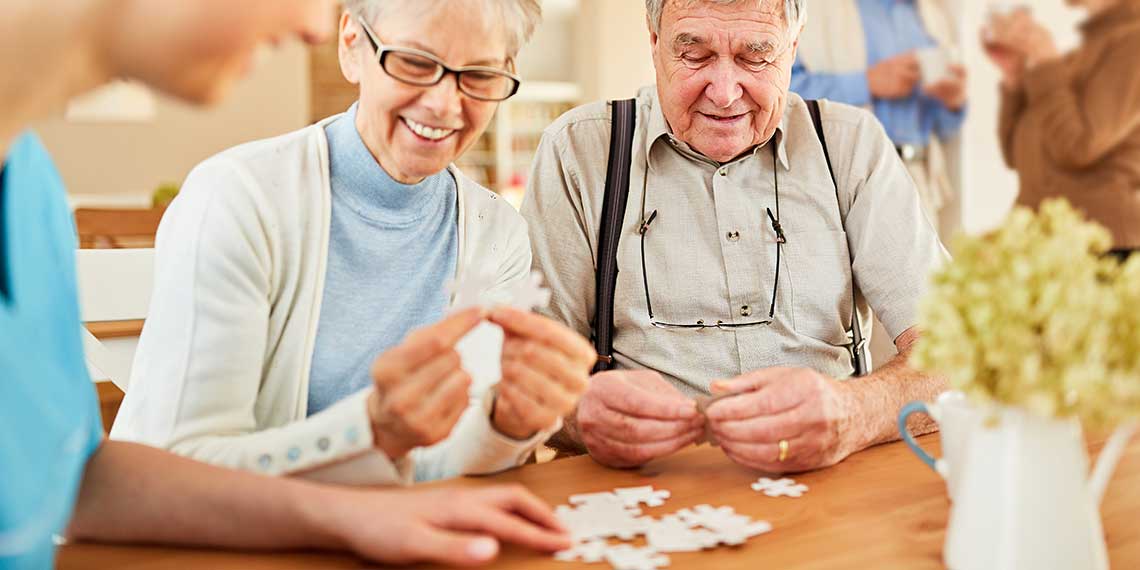 Senioren mit Demenz spielen ein Puzzle im Pflegeheim